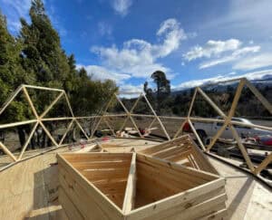 Estructura de triángulos de madera ensamblados sobre zócalo pintado con pintura asfáltica en terreno patagonico