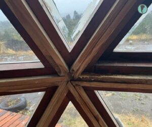 Encuentro interior de aberturas triangulares con signos de filtración entre marco y estructura del domo
